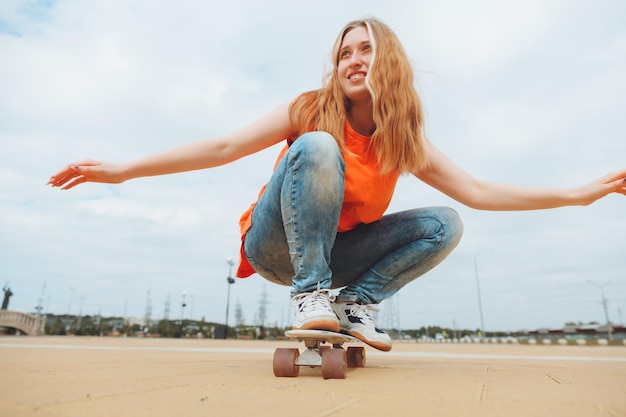 A beautiful young teenage girl rides a skateboard in sunny\
weather generation z