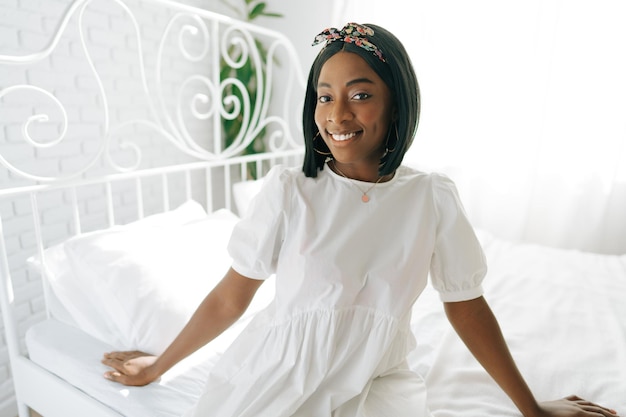 Красивая молодая задумчивая африканская женщина сидит в утренней постели