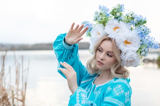 아름 다운 꽃 화 환과 파란색 수 놓은 드레스를 입고 아름 다운 젊은 우크라이나 여자