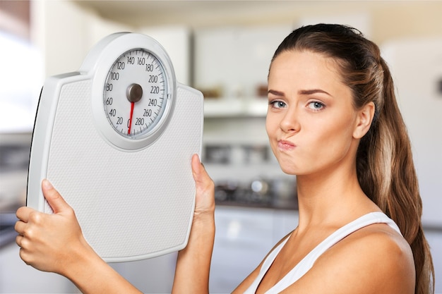 Beautiful young unhappy woman holding scales