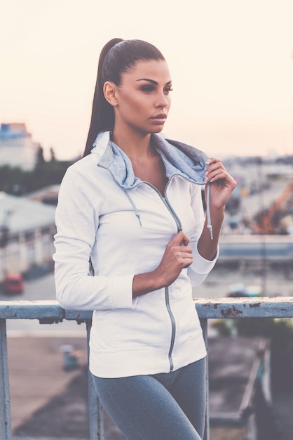 Beautiful young woman adjusting her sports clothes and looking away