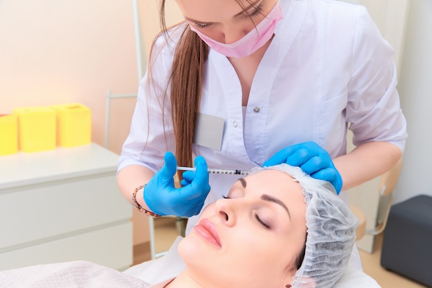 Beautiful young woman in aesthetic cosmetology clinic.