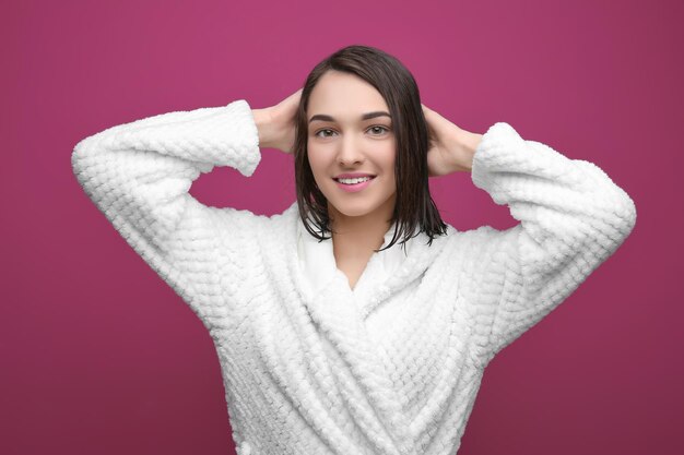 Beautiful young woman after shower on color background