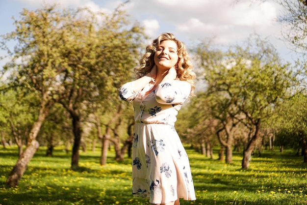 Красивая молодая женщина в яблоневом саду в весенний солнечный день - счастливые моменты