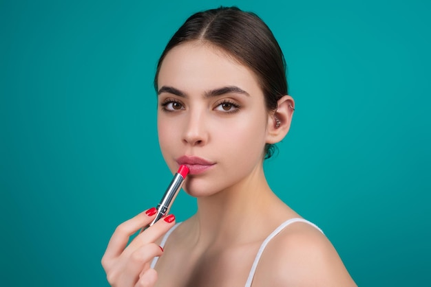 Beautiful young woman applying red lipstick on lips studio color background sexy girl applied