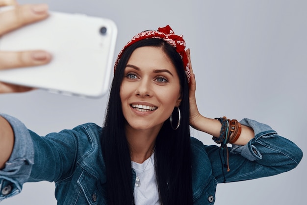 Foto bella giovane donna in bandana che fa selfie e sorride