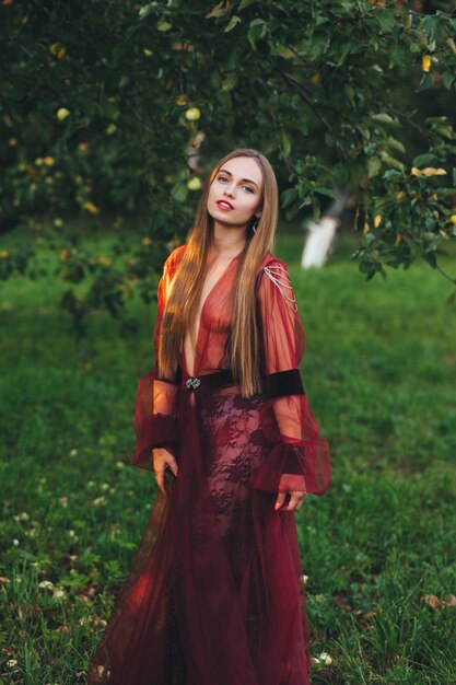 A beautiful young woman in a bard dress is gazing on in the field and the garden.