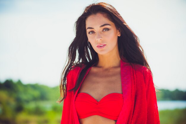 Beautiful young woman in beachwear walks on the sand