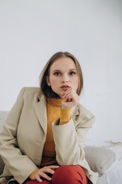 beautiful young woman in a beige jacket is sitting on the couch Businesswoman at home