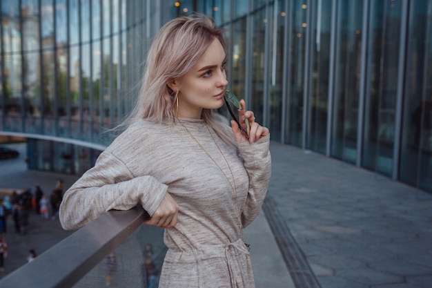 A beautiful young woman in a beige knit dress walks through the streets of Moscow, the famous and popular Zaryadye Park right in the center near the Red Square