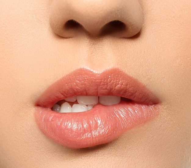 Beautiful young woman biting lip on grey background closeup