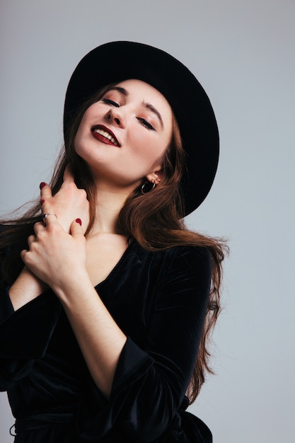 Beautiful young woman in black dress and hat on white background. Girl in black isolated