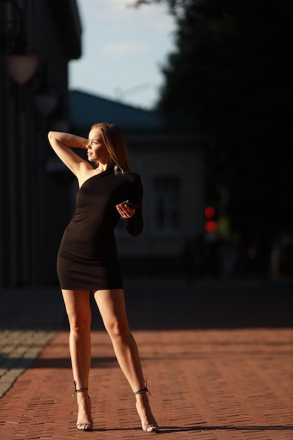 красивая молодая женщина в черном платье на прогулке летом
