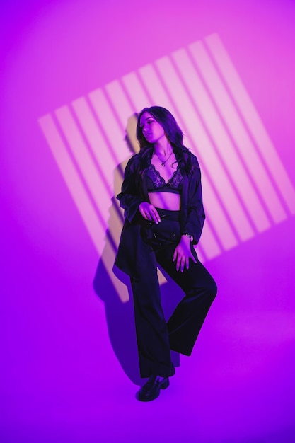 A beautiful young woman in a black suit stands on a white background Hard light