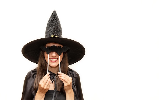 Beautiful young woman in a black witch costume at a party on a white background Halloween holiday concept