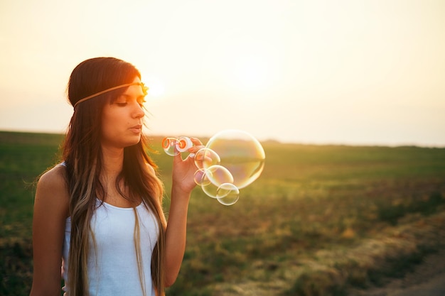 Foto bella giovane donna che soffia bolle durante il tramonto