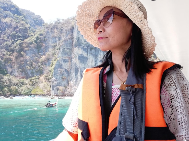 Photo 山に逆らって海のボートに乗った美しい若い女性