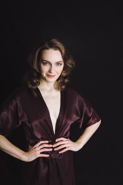 Beautiful young woman in brown dress on black background