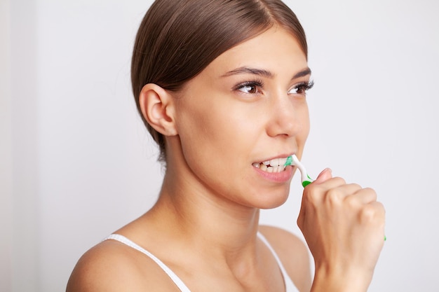 Photo beautiful young woman brush her teeth in the bathroom