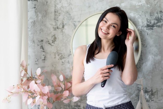 Foto bella giovane donna che spazzola i suoi capelli