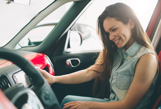 ディーラーで車を買う美しい若い女性。車のインテリアに座っている女性モデル