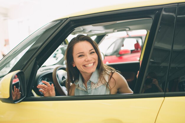 ディーラーで車を買う美しい若い女性。車のインテリアに座っている女性モデル