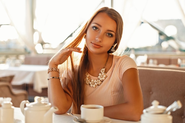 Bella giovane donna in un caffè che beve il tè