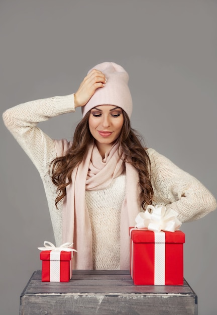 a beautiful young woman cannot decide which gift to choose, looks at a small and large box. the girl makes christmas shopping, meets the new year. shopping sale concept.