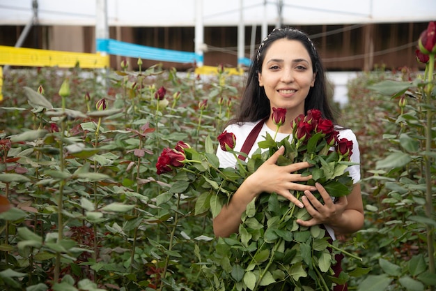 Beautiful young woman caring for roses in a greenhouse