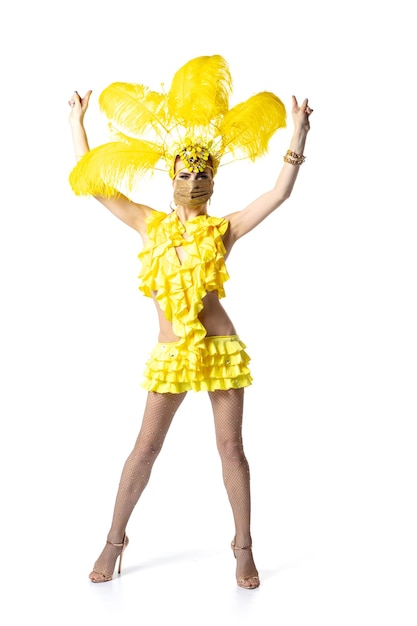 Beautiful young woman in carnival, stylish masquerade costume with feathers dancing on white studio background. Concept of holidays celebration, festive time, dance, party, having fun