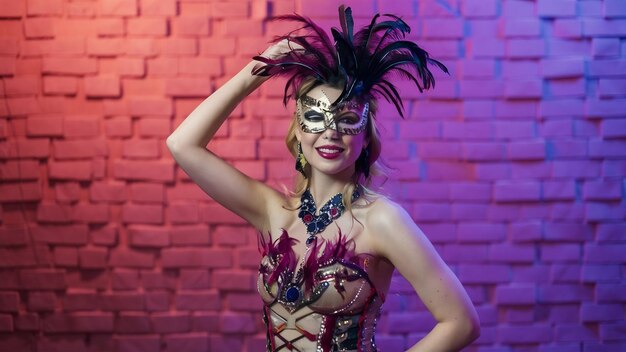 Beautiful young woman in carnival stylish masquerade costume with feathers on gradient wall in neo