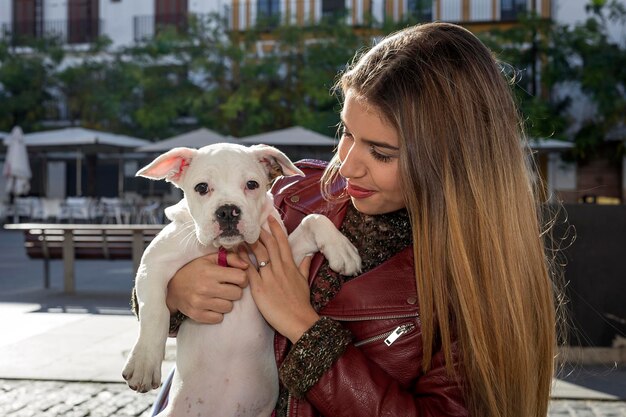 Foto bella giovane donna che porta un cane per la strada della città