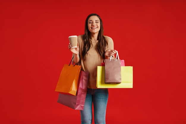 Beautiful young woman in casual clothing carrying shopping bags and smiling