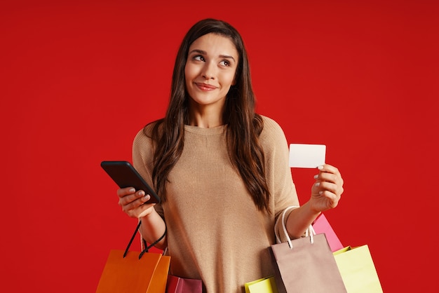 Beautiful young woman in casual clothing carrying shopping bags and smiling