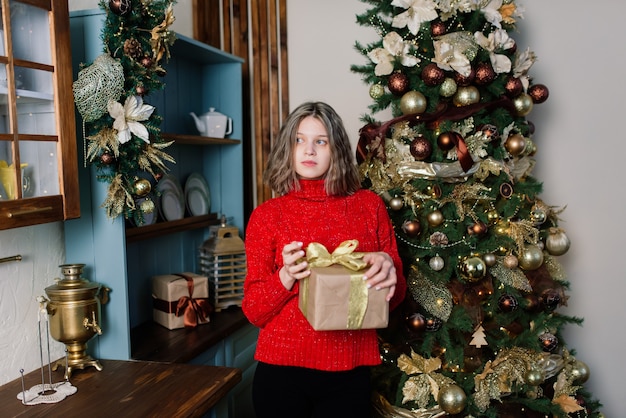 Красивая молодая женщина празднует рождество дома, развлекаясь при открытии подарков