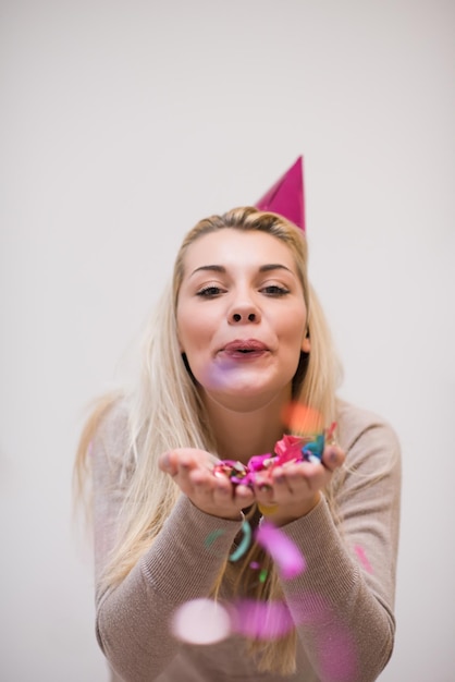 beautiful young woman celebrating new year and chrismas party while blowing confetti decorations to camera