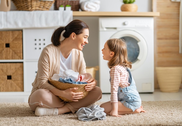 美しい若い女性と子供の女の子の小さなヘルパーは楽しんで笑っています