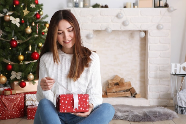 Beautiful young woman in a christmas interior with gifts place for text