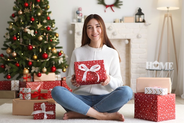 Beautiful young woman in a christmas interior with gifts place for text