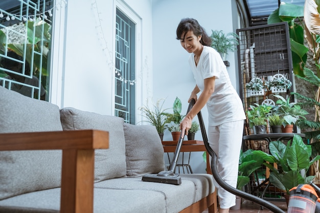 Beautiful young woman cleaning with vacuum cleaner at home