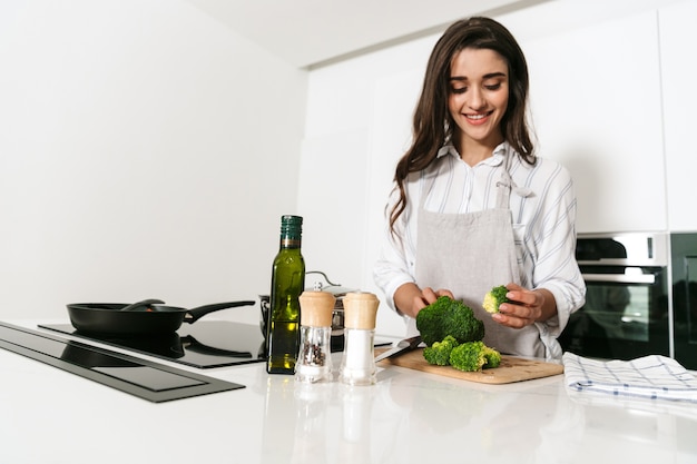 Bella giovane donna che cucina una cena sana in cucina