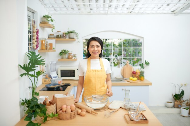 Beautiful young woman cooking pastry in kitchen