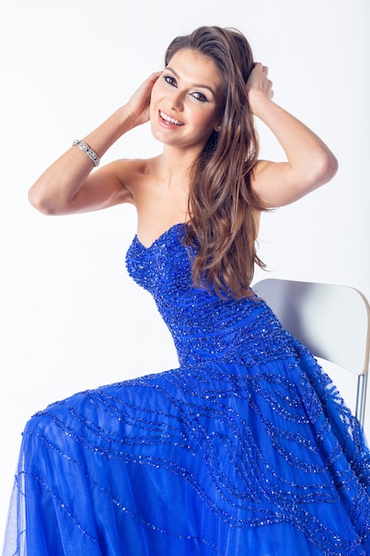 Beautiful young woman in a dark blue dress over a light gray wall