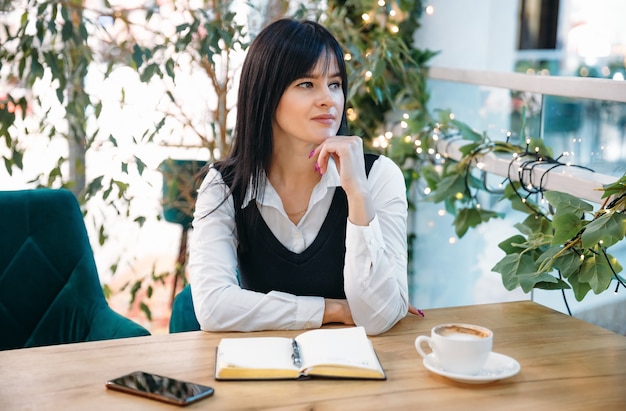 Beautiful young woman daydreaming about something while sitting in modern cafe bar