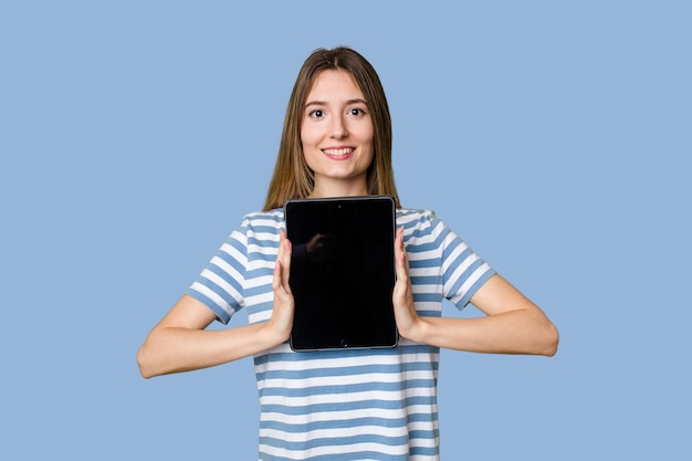 A beautiful young woman displays a sleek tablet showcasing her techsavvy and modern style