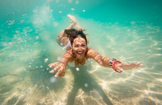 Beautiful young woman diving underwater in the sea.