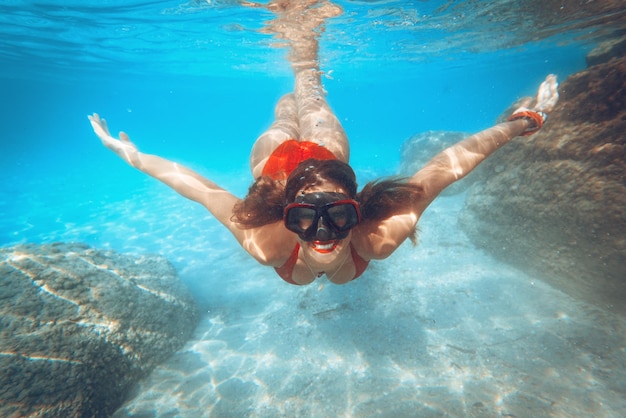 Beautiful young woman diving underwater in the sea.