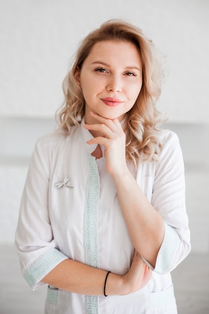 Фото Красивая молодая женщина-врач позирует в белом медицинском халате.