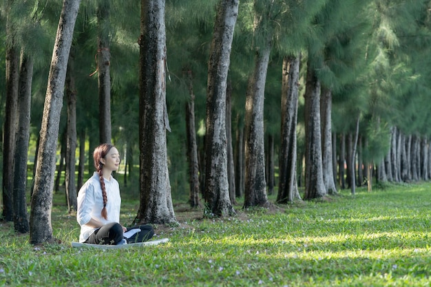 公園で瞑想とヨガをしている美しい若い女性