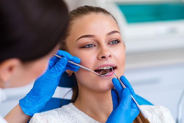 Beautiful young woman doing tooth examination in the dental office Portrait of smiling girl on a dental chair in dentistry